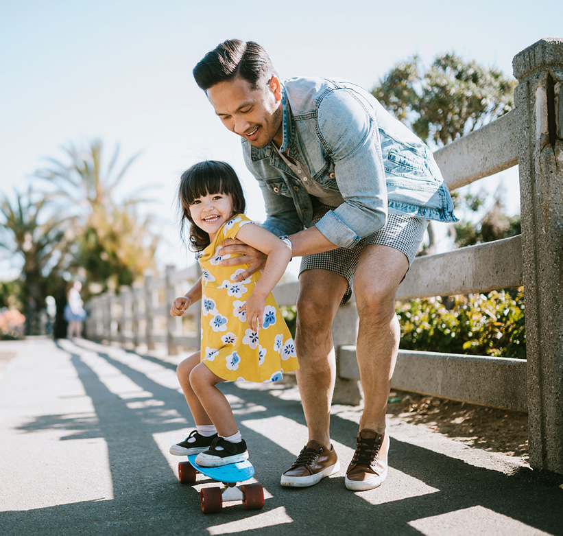 father teaching daughter to ride skateboard
