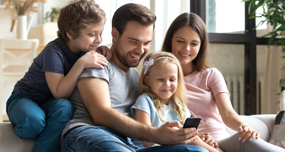 family sitting on couch using a mobile phone