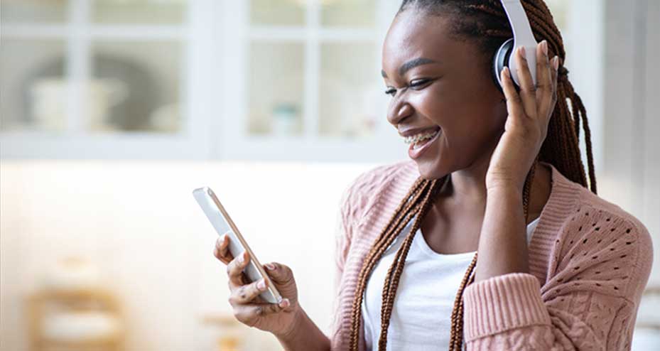 women with braces is wearing headphones listening to music on her phone