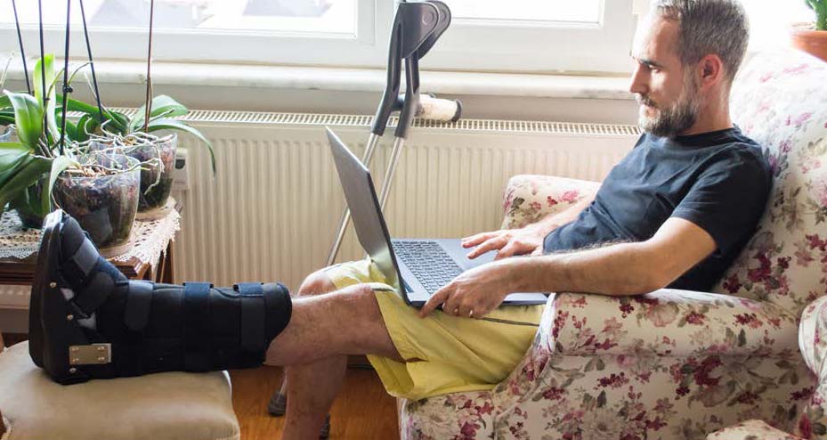 man with broken leg working on laptop