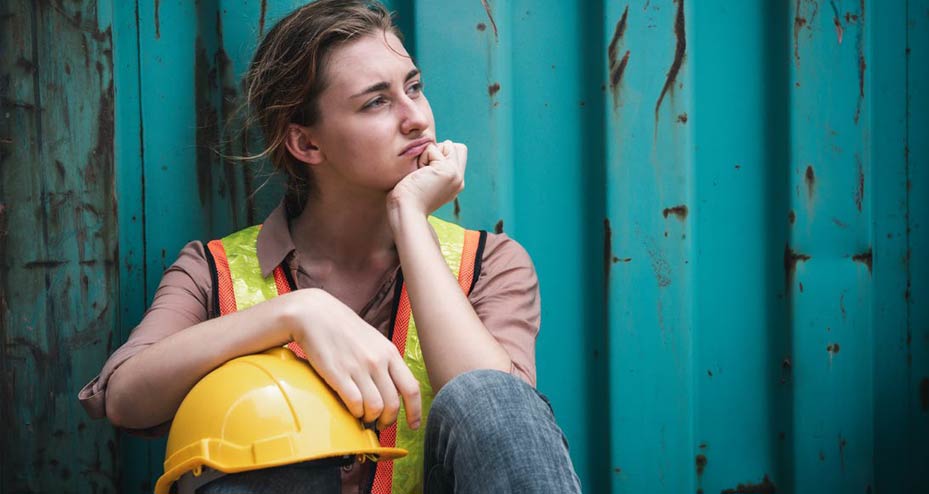 worker sitting on ground with hand under chin