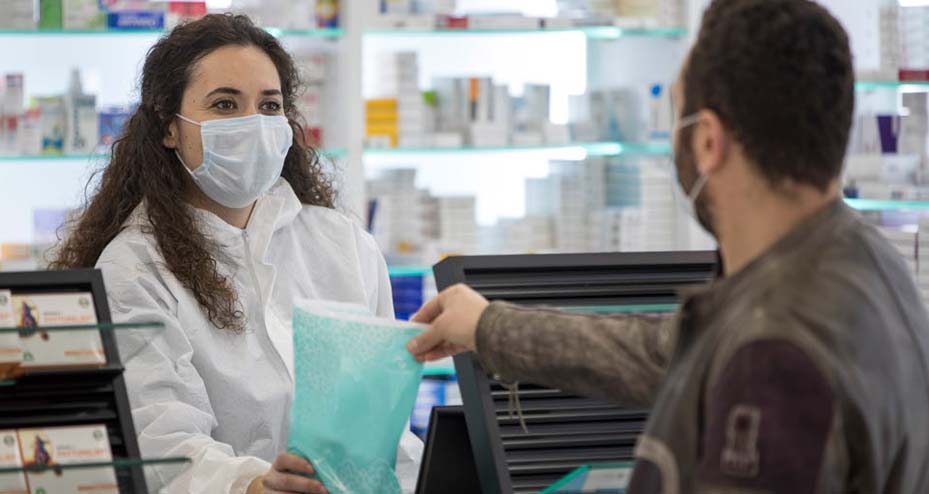 pharmacist handing bag to customer