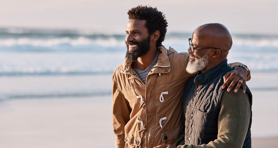 father and son standing on a beach smiling