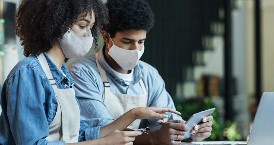 two masked employees working on tablet