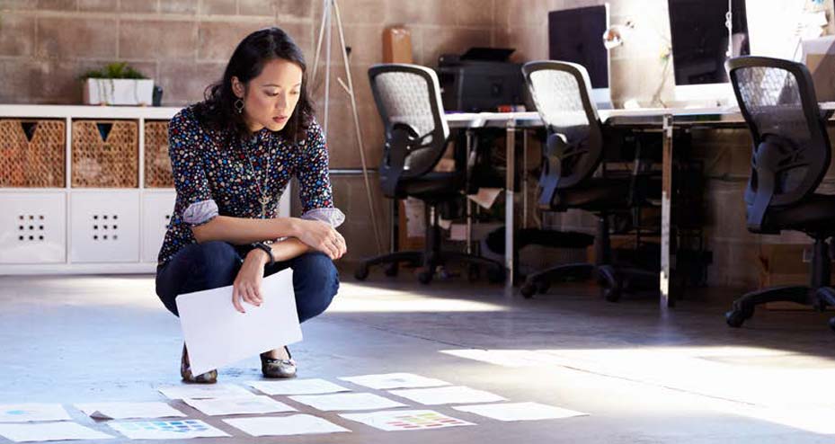 woman looking at papers laid out on the ground