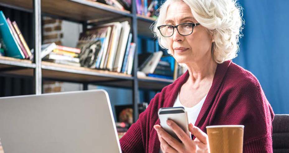 woman working on laptop looking at phone