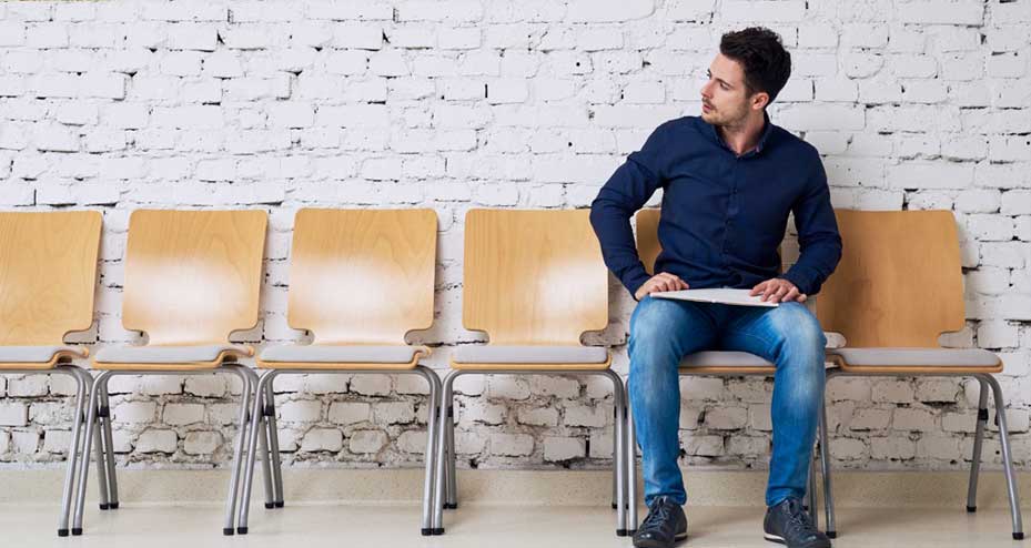 man sitting in a row of empty chairs