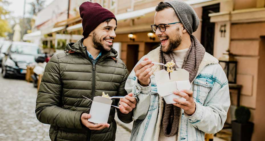 two guys walking and eating takeout